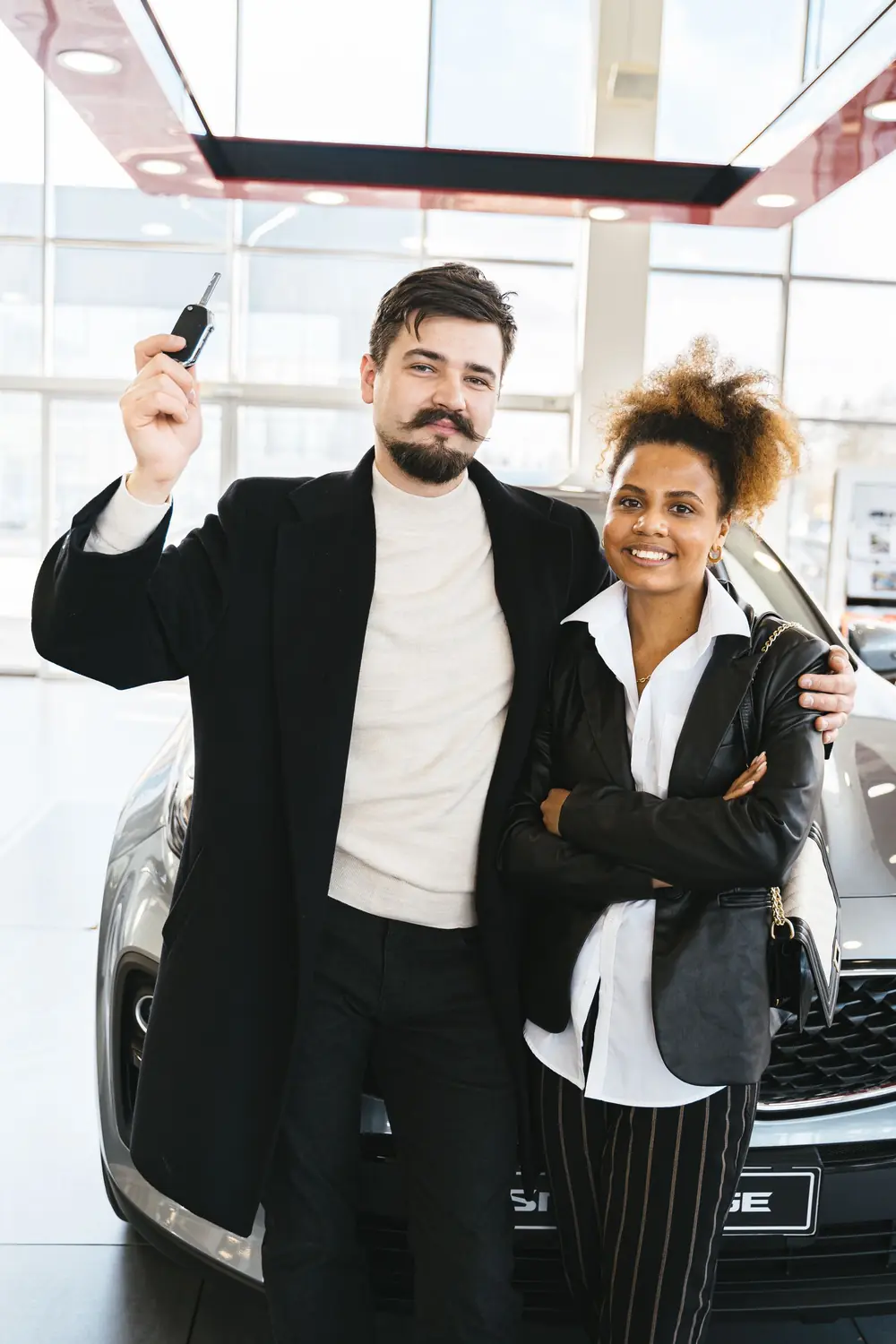 Casal com as chaves do carro novo na concessionária